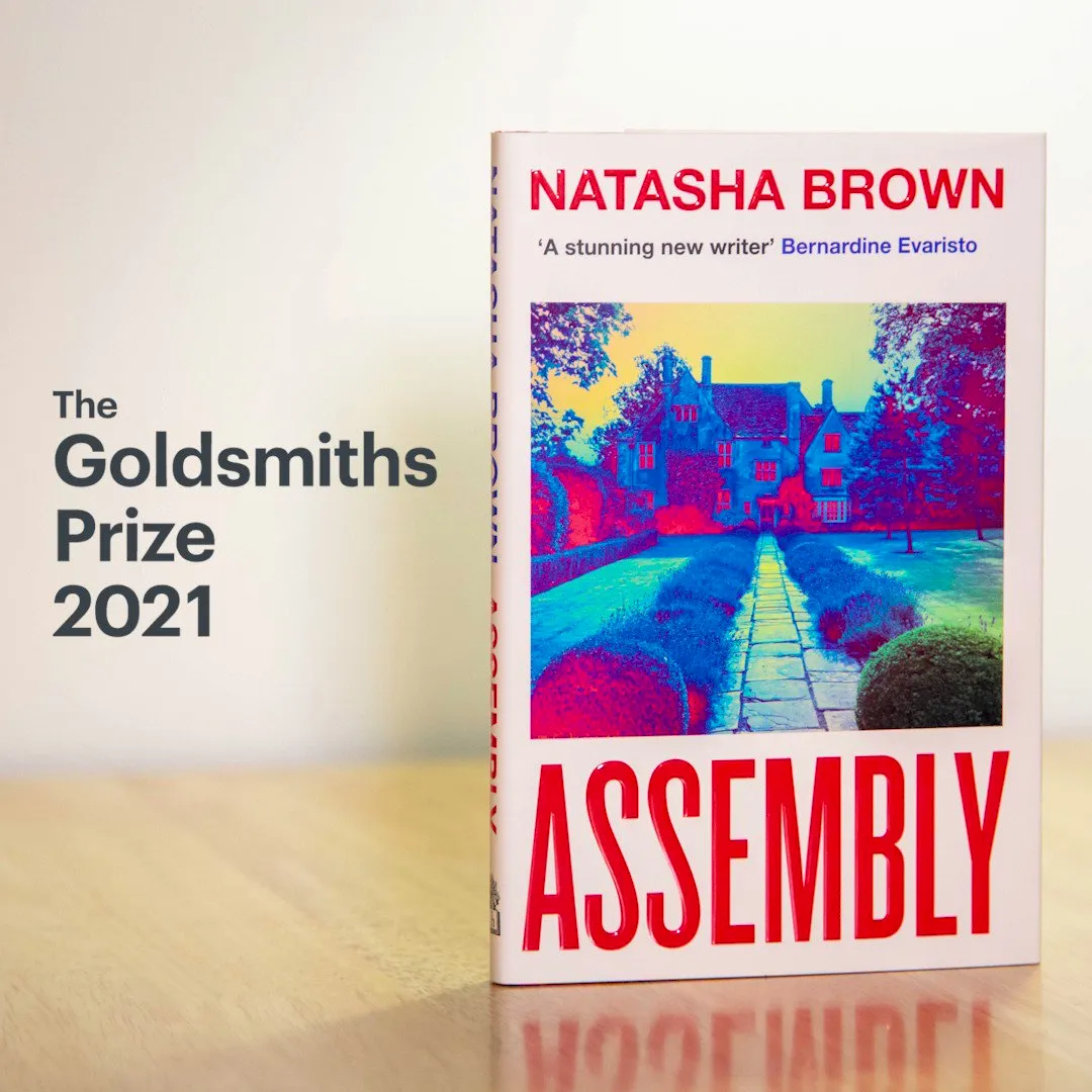 A copy of the novel Assembly standing on a shiny wooden table